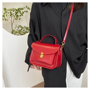 Détail du sac messager rouge montrant la texture cirée lisse et la boucle en métal doré
