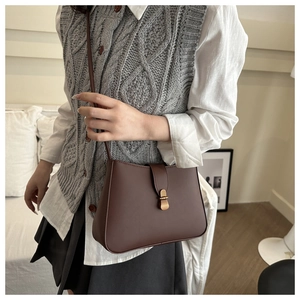 Close-up of a dark brown vintage leather shoulder bag with a stylish gold buckle