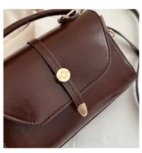 Detail of dark brown retro shoulder bag with glossy PU leather and round gold clasp