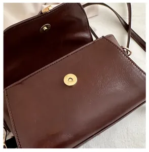 Detail of the vintage brown faux leather bag showing secure magnetic buckle and interior layout