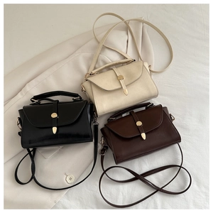 Detailed view of three minimalist leather crossbody bags in black, beige, and dark brown