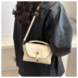 Detailed side view of cream leather crossbody bag with golden metal buckle on a model