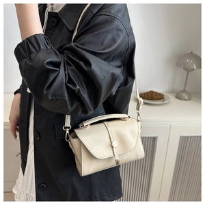 Detail showing creamy white square leather bag with gold buckle on model's side