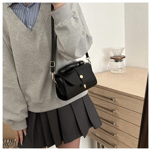 Detailed view of black matte leather small square bag with elegant golden metal buckles