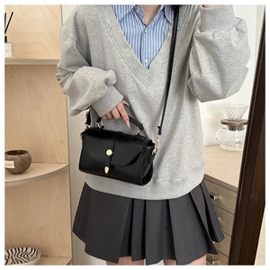 Detail view of black PU leather bag with gold round metal lock and adjustable strap