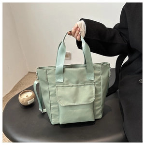 Detail of mint green nylon tote bag featuring front pocket and adjustable shoulder strap
