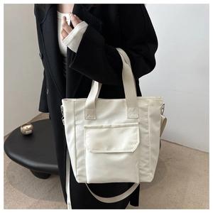 White nylon tote bag with front flap pocket and adjustable strap shown on model