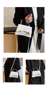 Close-up of white crossbody bag with gold chain decoration and smooth leather texture
