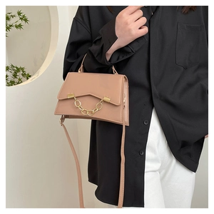 Détails de la texture du cuir nude et de la chaîne dorée sur le sac à main tendance