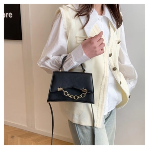 Détail du sac boîte noir avec chaîne dorée décorative et finition en cuir mat élégant