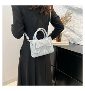 Détail du sac à main bleu clair plissé avec nœud papillon et breloque cœur en métal doré