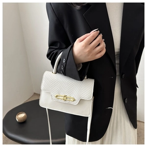Detail of white PU leather bag featuring woven flap and gold U-shaped metal lock
