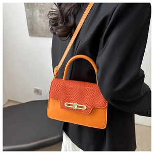 Detail of crossbody bag featuring orange textured weave and sleek golden metal lock