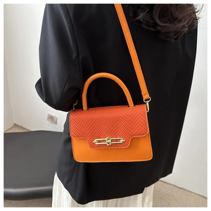 Detail of orange plaid crossbody bag featuring a golden geometric clasp and leather strap