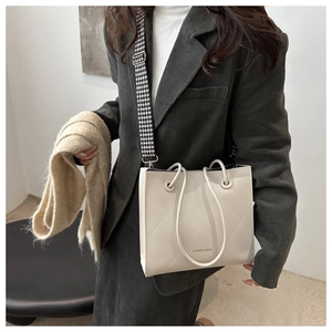 Dettaglio della borsa shopper beige trapuntata con scritta dorata e tracolla pied de poule