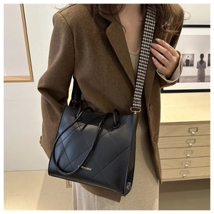 Borsa tote nera trapuntata con tracolla pied-de-poule indossata da modella in blazer