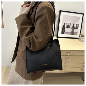 Dettaglio della borsa tote in pelle nera trapuntata con scritte dorate sulla spalla