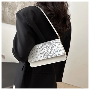 Detail of white baguette bag with crocodile texture flap and gold hardware accents