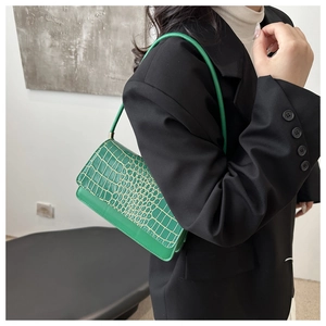 Detail view of bright green crocodile embossed shoulder bag worn under the arm