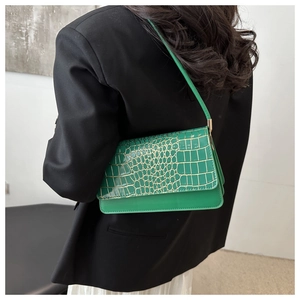 Detail of bright green faux crocodile leather underarm bag on black suit jacket