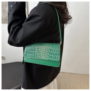 Détail de texture crocodile verte sur un sac en cuir verni avec gaufrage doré
