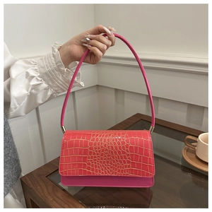 Détail du petit sac à main rose rouge à motif crocodile et finitions dorées