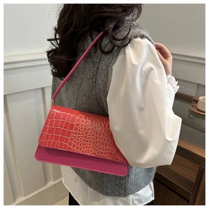 Detail of bright pink faux crocodile leather shoulder bag showing texture and golden clasp