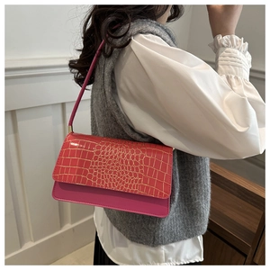 Detail of rose pink shoulder bag showing faux crocodile embossing and smooth leather texture