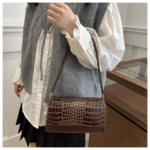 Détail de la texture crocodile marron foncé avec bordure dorée et ferrures métalliques