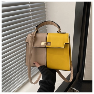 Détail d'un sac à main bicolore jaune et kaki avec fermoir doré et finitions soignées