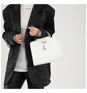 Gros plan du sac bandoulière blanc avec pendentif cerf doré et finitions