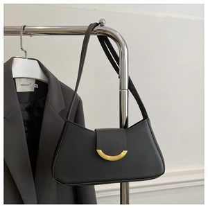 Detailed view of black minimalist baguette bag with elegant golden crescent hardware clasp