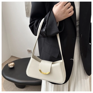 Detail view of cream-colored shoulder bag with gold metal buckle and leather texture