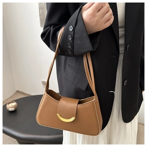 Brown leather baguette bag with gold hardware detail on a model in a black blazer