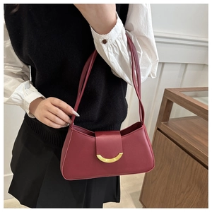 Detail of burgundy leather underarm bag featuring a vintage golden crescent metal buckle