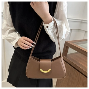 Close-up of brown leather shoulder bag featuring a signature gold crescent buckle detail