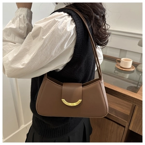 Brown vintage baguette bag with gold metal buckle worn as a stylish shoulder underarm bag