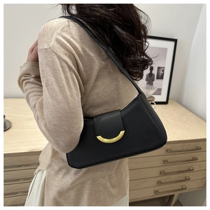 Detail of minimalist black underarm bag with elegant gold crescent buckle on shoulder