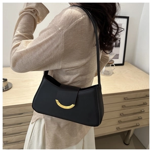 Detail of a vintage black leather underarm bag with an elegant golden crescent buckle