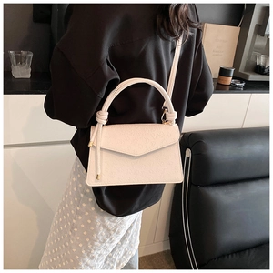 Close-up of white embossed leather crossbody bag with knot handle and gold hardware