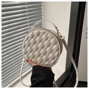 Detail of white quilted round handbag with gold double zippers and textured surface