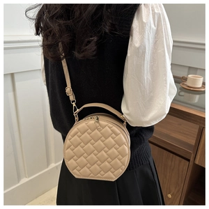 Close-up of beige round crossbody bag with quilted texture and gold metal hardware detail