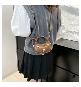 Detail of brown mini crossbody bag with five silver dome studs and leather shoulder strap