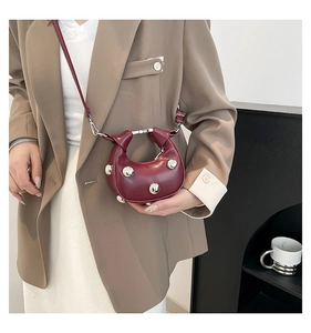 Close-up of burgundy crescent bag featuring silver stud detailing and leather strap