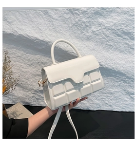 Detailed view of white quilted crossbody bag with textured cube pattern and top handle