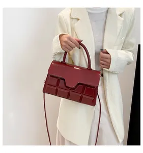 Dettaglio borsa bordeaux in pelle verniciata con trama a cioccolato 3D su modella