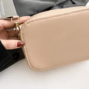 Detail van beige crossbodytas met lederen textuur en goudkleurige metalen accenten