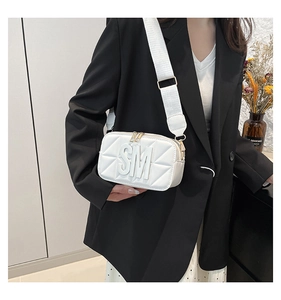 Detail van witte gewatteerde crossbodytas met dubbele ritsen en brede schouderband