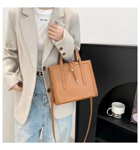 Close-up of tan leather square handbag with top handle and tassel zipper detail for office