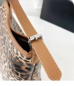 Dettaglio della tracolla regolabile in pelle marrone con fibbia argento su borsa leopard